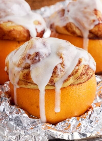 campfire cinnamon rolls drizzled with icing stuffed into an orange