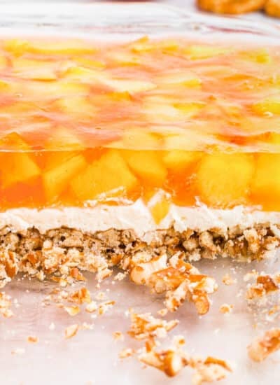 Side view of the peach pretzel salad showing the three layers: pretzel crust, creamy middle, and peach jello with peach chunks.